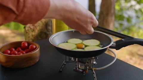 Close-up of female hands cracking a quail egg into a frying pan at the campsite. Stock-Footage 290388059