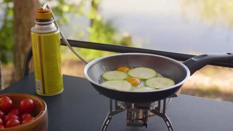 Close-up of female hands cracking a quail egg into a frying pan at the campsite. Stock-Footage 290388273