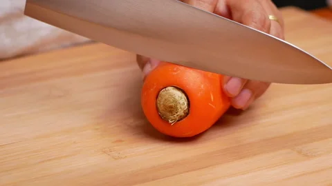 Close-up of female hands cutting raw carrot on the cutting board. Видео 158657948