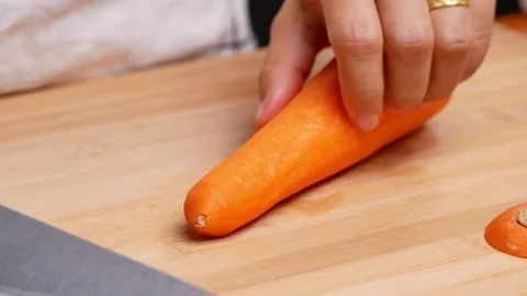Close-up of female hands cutting raw carrot on the cutting board. Stock Footage 158657951