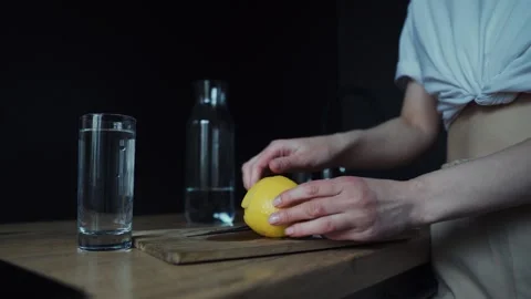Close-up of female hands cutting off a slice of lemon and throwing it into a Stock Footage 255984799