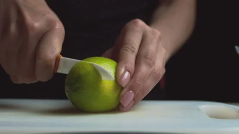 Close up of female hands on a dark background slices a lemon Stock Footage 135259555
