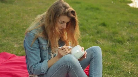 Close-up of female hands drawing a pattern with flowers on a white cup. Girl Stock Footage 75877115
