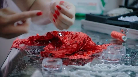 Close up female hands embroidery pattern on red fabric with beads Video stock 126915441