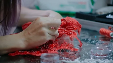 Close up female hands embroidery pattern on red fabric with beads Video stock 126915445