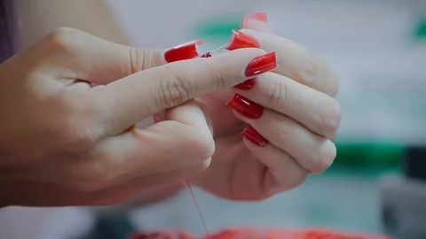 Close up female hands embroidery pattern on red fabric with beads Video stock 126915446