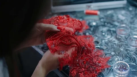 Close up female hands embroidery pattern on red fabric with beads Video stock 126915452