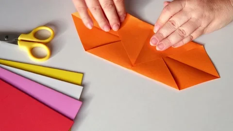 Close-up of female hands fold colored paper, makes hearts using origami techn Stock Footage