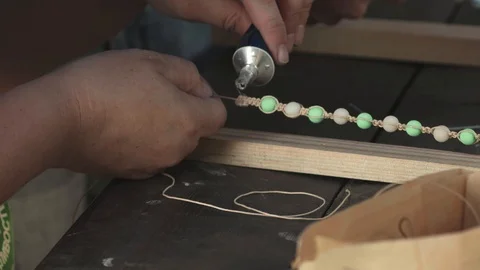 Close-up of female hands glueing a thread with beads, making a jewelry bracelet Stock Footage 119647108