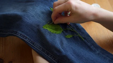 Close-up female hands making handmade color embroidery pattern on jeans using Stock Footage 101463008