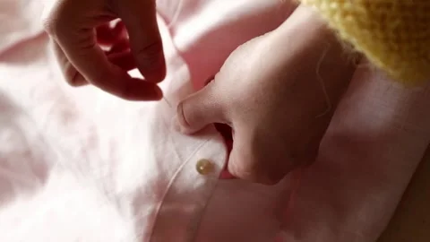 Close up of female hands manually sews button to pink linen fabric using needle. Stock Footage 316920527