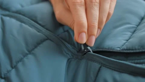 Close-up of female hands open lock on winter emerald green jacket, down jacket Stockbeeldmateriaal 224868036
