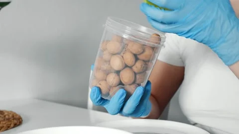 Close-up female hands opens a jar of whole walnuts and pours them into a bowl. Video stock 151994479