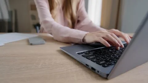 Close-up female hands with papers sorting documents typing on laptop at table in Stock Photos