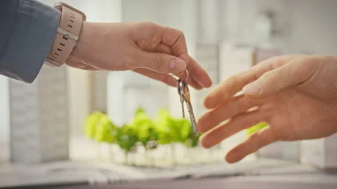 A close-up of female hands passing keys to a male client in a modern real es Stock Footage 341490478