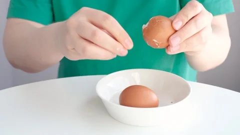 Close-up of female hands peeling the shells of boiled eggs against a white table Stock Footage 336170170