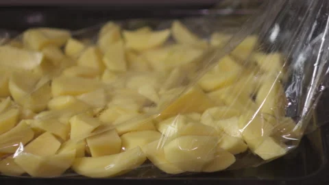 Close-up of Female Hands Placing Sliced Potatoes into Roasting Bag 库存影片 335229735