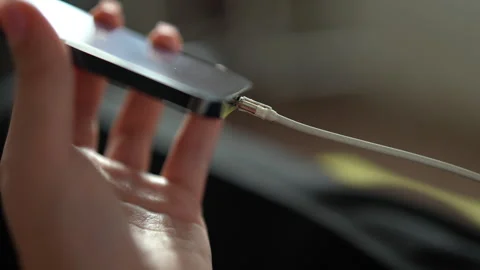 Close-up of female hands plugging white lightning cable into smartphone to Stock-Footage 342768330