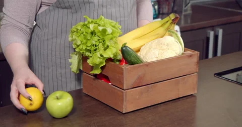 Close-up of female hands of a plus size model laying out fresh vegetables and Stock Footage 149625225