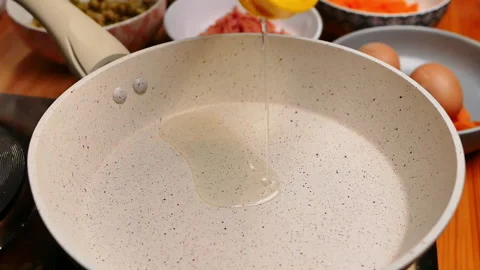 Close up of female hands pouring vegetable oil into the a frying pan. Stock Footage 158658329