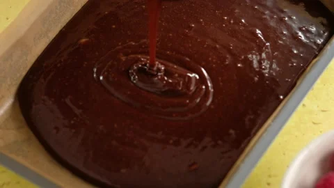 Close-up of female hands preparing dough for a chocolate cake and pouring the Stock Footage 145088708