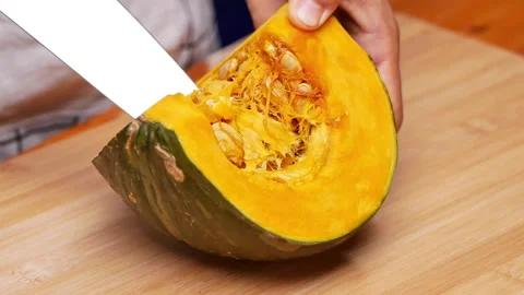 Close up of female hands preparing pumpkin for cooking, remove seeds with knife  Stock Footage 158657888