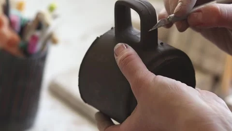 A close up female hands process a cast clay mug before drying. Stock Footage 275114701