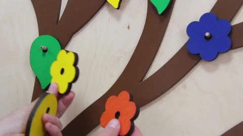 Close-up female hands remove and put multicolored wooden flowers on wooden panel Stock Footage 140016427