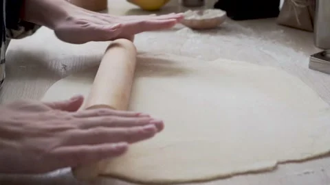 Close-up, female hands roll out the dough with a wooden rolling pin on the table Stock Footage 147547576