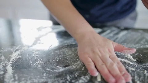 Close-up of female hands rolling dough with pin on wooden table Stock Footage 78927238