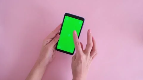 Close-up of female hands scroll phone with green screen on pink background Stock Footage 234313448