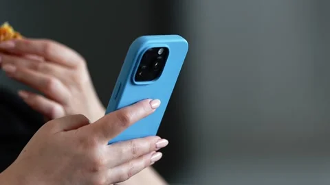 Close Up Female Hands Scrolling on Smartphone While Eating Snack Stock Footage 330354680