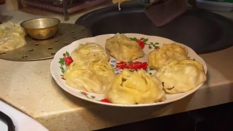 Close-up of female hands serving cooked manti dumplings onto a plate Stock Footage 336707923