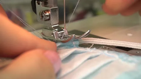 Close-up female hands sew a protective mask.sew an elastic band Stock Footage 140142101