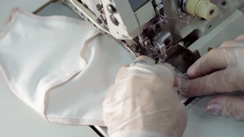 Close-up female hands sew a protective medical face mask on a sewing machine. Stock Footage 144680787