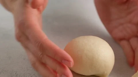 Close-up of female hands shape a round bun for hamburgers from dough on a table Video stock 145093550