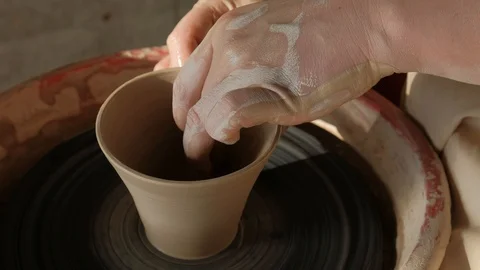 Close-up female hands shaping up a cup from raw clay on pottery wheel Stock Footage 101702709