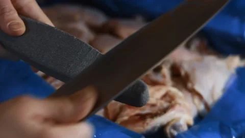 Close-up of female hands sharpening knife in the kitchen before cutting the meat Stock Footage 145707708