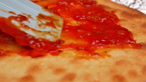 Close up of female hands spreading tomato sauce on pizza dough with a spatula. Vídeos de archivo 158669255