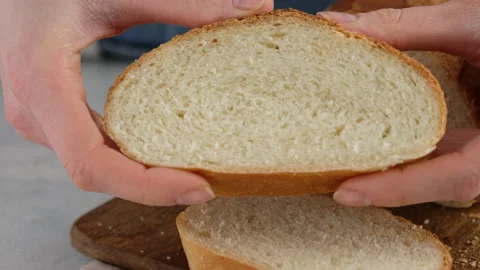 Close-up of female hands squeeze a piece of wheat bread on a wooden board on a Stock Footage 146142272