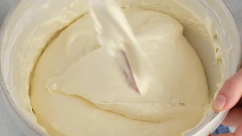 Close-up female hands stir flour with beaten eggs to make a sponge cake. Mixing Stock Footage 148569738