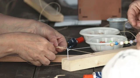 Close-up of female hands stringing beads on a thread, making a jewelry bracelet Stock Footage 119646792