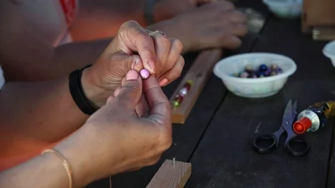 Close-up of female hands stringing beads on a thread, making a jewelry bracelet Stock Footage 119646920
