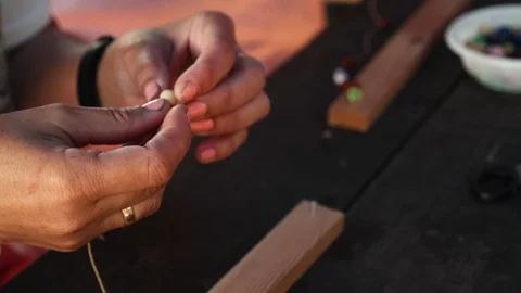 Close-up of female hands stringing beads on a thread, making a jewelry bracelet Stock Footage 119647042