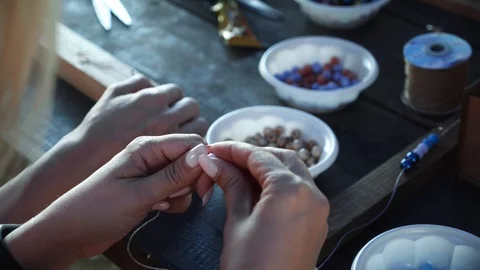 Close-up of female hands stringing beads on a thread, making a jewelry bracelet Stock Footage 119647146