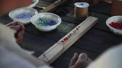Close-up of female hands stringing beads on a thread, making a jewelry bracelet Stock Footage 119647261