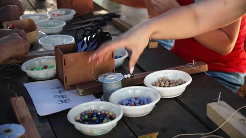 Close-up of female hands stringing beads on a thread, making a jewelry bracelet Stock Footage 119647301