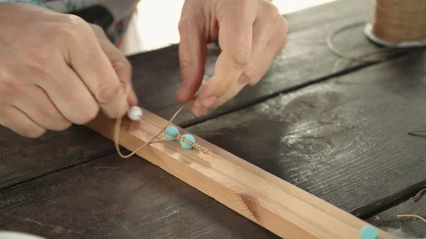 Close-up of female hands stringing beads on a thread, making a jewelry bracelet Stock Footage 119647366