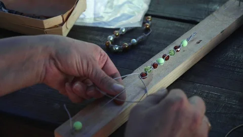 Close-up of female hands stringing beads on a thread, making a jewelry bracelet Stock Footage 119647511