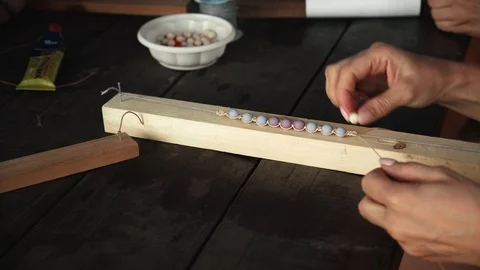 Close-up of female hands stringing beads on a thread, making a jewelry bracelet Stock Footage 119647744
